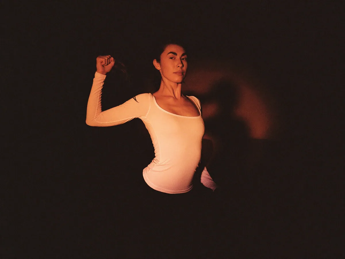 An adult athlete holding a strong yoga pose in a single warm light.